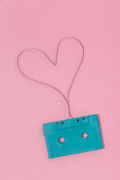 Retro cassette with heart shaped tape on pink surface