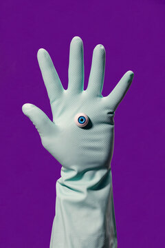 Crop person in glove with fake eye in violet studio