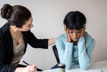 Caucasian woman therapist providing psychological help to female african american patient,...