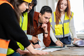 South american engineer supervisor at construction site with his multiethnic work team setting...