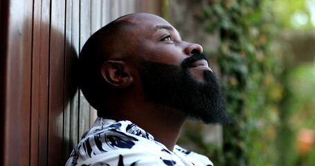 Pensive African man taking a deep breath outside feeling relaxed