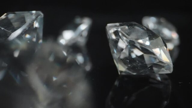 Shiny classic shape diamonds on black surface and background. Camera sliding through various precious stones on reflective surface