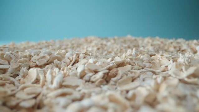 Passing over mountains of oat grains with light blue background. Healthy and nutritious grain for making oat meal and milk and other healthy diet food. Whole grain and vegan friendly and gluten free