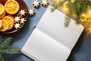 Top view mockup image of white blank notebook with christmas decorations, oranges and fir brunches...
