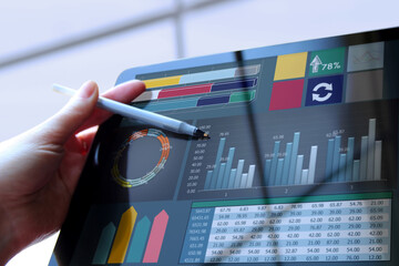 Business woman working and analyzing financial figures on a graphs on a tablet