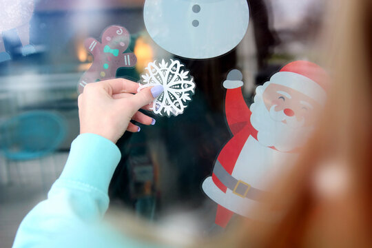 Girl  decorating  snowflake sticker on  a window glass  to welcome Christmas and New Year.