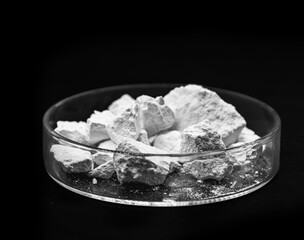 Calcium Chloride flakes, salt in solid state, used in brine for refrigeration machines, road dust and ice control, in cheese and in cement. Industrial use, isolated black background, copyspace