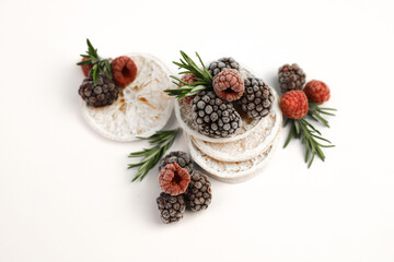 Obraz na płótnie Canvas sweet delicious berry dessert of white dried oranges garnished with juicy raspberries and blackberries and rosemary sprigs on a white background. for signboards, labels, postcards, leaflets, shop bann