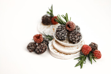 sweet delicious berry dessert of white dried oranges garnished with juicy raspberries and blackberries and rosemary sprigs on a white background. for signboards, labels, postcards, leaflets, shop bann