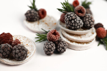 sweet delicious berry dessert of white dried oranges garnished with juicy raspberries and blackberries and rosemary sprigs on a white background. for signboards, labels, postcards, leaflets, shop bann