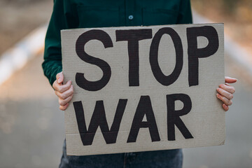 Ukrainian girl protests war, holds banner, placard  with inscription message text Stop War, street...