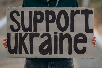 Ukrainian girl protests war, holds banner, placard  with inscription message text Support Ukraine,...