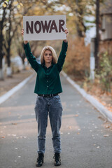 Ukrainian girl protests war, holds banner, placard  with inscription message text No War, street...