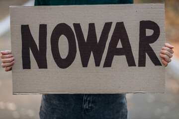 Ukrainian girl protests war, holds banner, placard  with inscription message text No War, street...