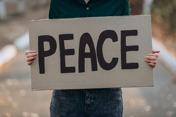 Ukrainian girl protests war, holds banner, placard  with inscription message text PEACE, street...