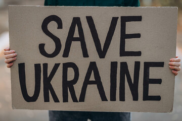 Ukrainian girl protests war, holds banner with inscription message text SAVE UKRAINE, street...