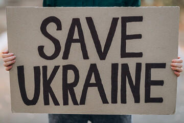 Ukrainian girl protests war, holds banner with inscription message text SAVE UKRAINE, street...