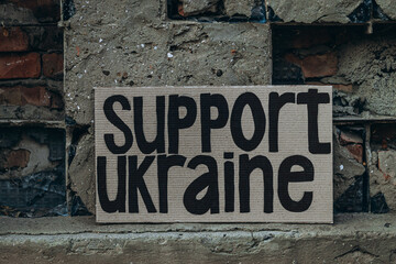Ukrainian protest against war with banner, placard  with inscription message text Support Ukraine, ruined city background. Crisis, peace, Russian aggression invasion concept. anti-war demonstration.