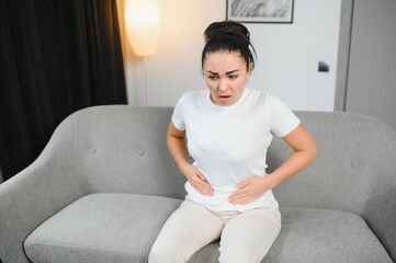 Young woman suffering from menstrual cramps at home. Gynecology