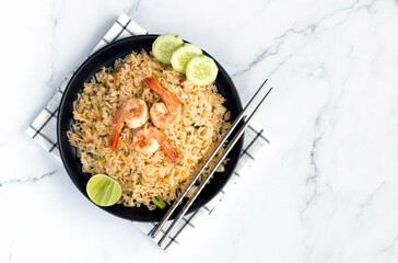 Traditional Thai fried rice with shrimp, tomato, egg, lime, cucumber, eco-friendly chopsticks on white background. Top view, copy space.	

