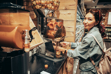 A girl squeezes fresh orange juice in a juicer in a supermarket