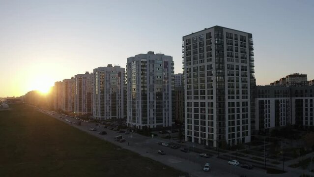 Sunset street with a row of tall residential buildings. Stock footage. New city area.