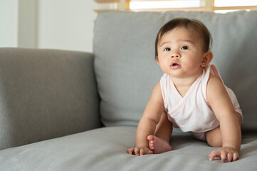 Portrait of baby girl sitting on sofa at home, family, child, childhood and parenthood concept