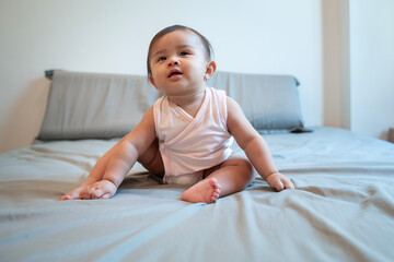 Fototapeta premium Portrait of baby girl sitting on sofa at home, family, child, childhood and parenthood concept