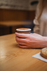 Close up shot of cup of coffee held by young woman inside a cafe