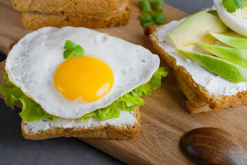 Sandwiches with curd cheese, fried egg, avocado and herbs