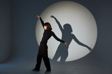 Teenage girl dances in a spotlight. The play of light and shadow.