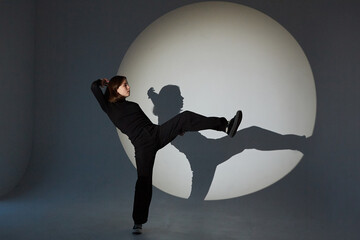 Teenage girl dances in a spotlight. The play of light and shadow.