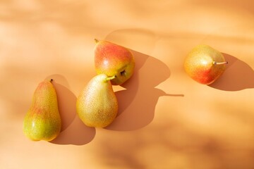 Ripe juicy yellow pears on an orange background in natural light with sunny shadows. Selective focus.