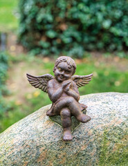 sch&ouml;ner Engel aus Gusseisen sitzt auf einem Grabstein auf einem Friedhof in Hamburg