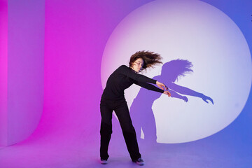 Teenage girl dances in a spotlight. The play of light and shadow.