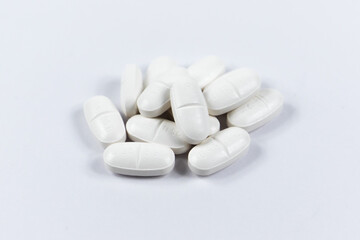 Fototapeta na wymiar many white oval medical tablets for humans and animals, medicinal antibiotics pills medicine closeup