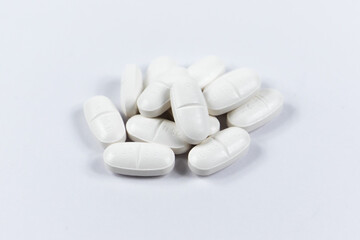 many white oval medical tablets for humans and animals, medicinal antibiotics pills medicine closeup