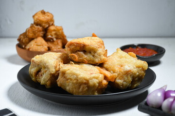 Selective Focus Gorengan or Fried tofu is a type of fried food made from tofu, flour and filled with bean sprouts on a black plate. Fried food is one of the favorite snacks in Indonesia.