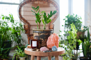 a plant, a salt lamp, a candle and crystals on a wooden chair in a bright room