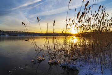 Sunset in winter on the shore of a freezing lake.