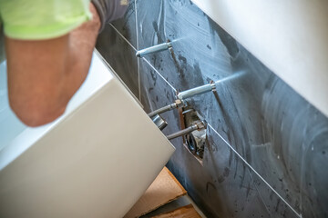 Plumber installs a toilet in a new bathroom. Moving to a new house concept