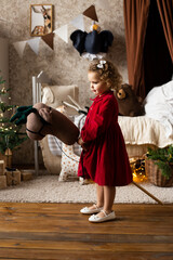 Fototapeta na wymiar girl on toy horse in Christmas home. Merry Christmas and Happy Holidays