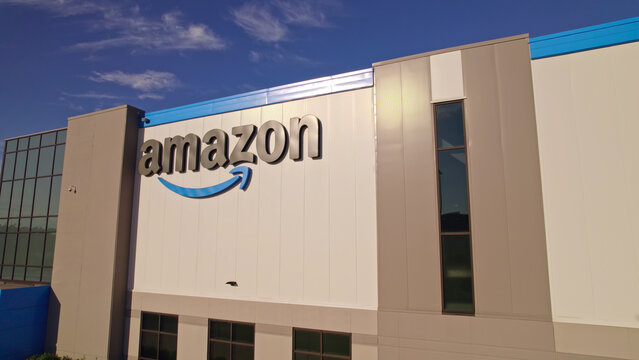 Toronto, Ontario, Canada - September 11, 2022: Amazon warehouse building headquarter and close-up logo of the company at golden hour evening. Technology company developed international e-commerce.