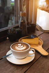 Hot coffee latte with latte art milk foam in cup mug and Homemade chocolate cake wood desk on wood desk on top view. As breakfast In a coffee shop at the cafe,during business work concept