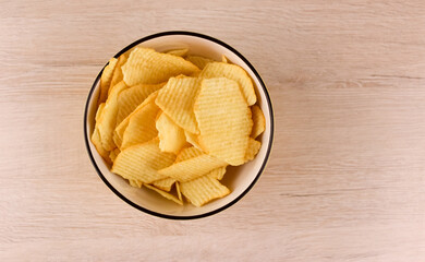 Chips in a deep plate on a wooden background