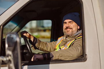 Smiling professional truck driver driving his truck and looking at camera