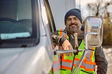 Portrait of happy truck driver by his vehicle looking at camera.