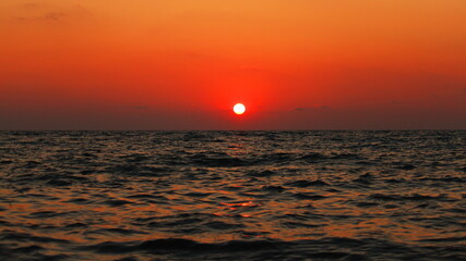 unusual sunset of the red sun over the sea wide format
