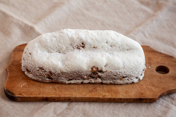 Homemade Christmas Stollen Bread on a rustic wooden board, side view.