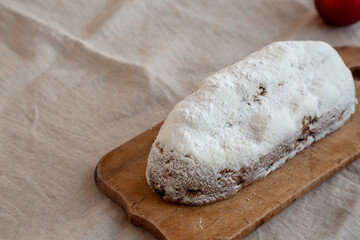 Homemade Christmas Stollen Bread on a rustic wooden board, side view. Copy space.